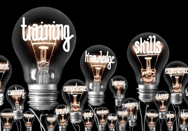 Photo of light bulbs with shining fibers in a shape of TRAINING, SKILLS and KNOWLEDGE concept related words isolated on black background